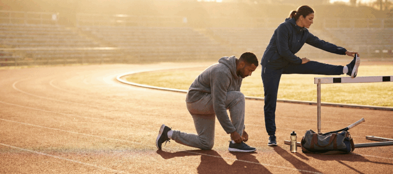 Un homme et une femme en étirements sur une piste d'athlétisme